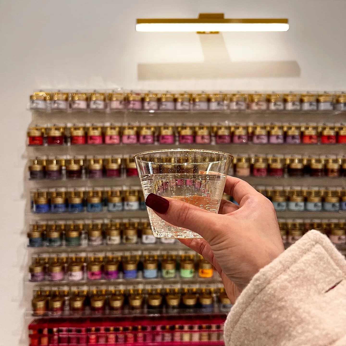 A guest with a drink choosing a color at the polish wall