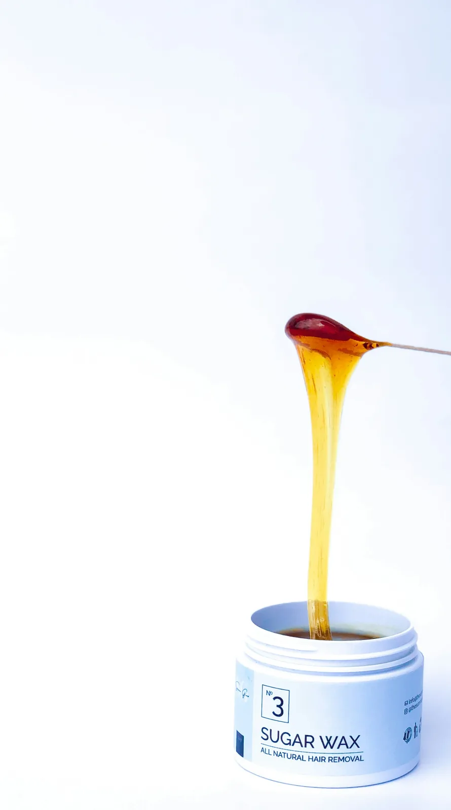 A jar of sugar wax with a wooden spoon